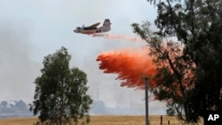 An air tanker drops a load of fire retardant while fighting a large grass fire, July 27, 2015, in Elverta, California.