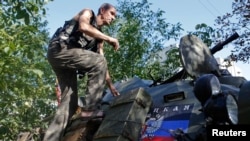 A pro-Russian separatist climbs atop an armored personnel carrier as he guards a position in the eastern Ukrainian town of Ilovaysk Aug. 31, 2014.