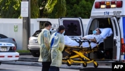 Para petugas medis mengeluarkan pasien dari ambulans di luar unit gawat darurat RS Coral Gables Hospital dekat Miami, 30 Juli 2020. 