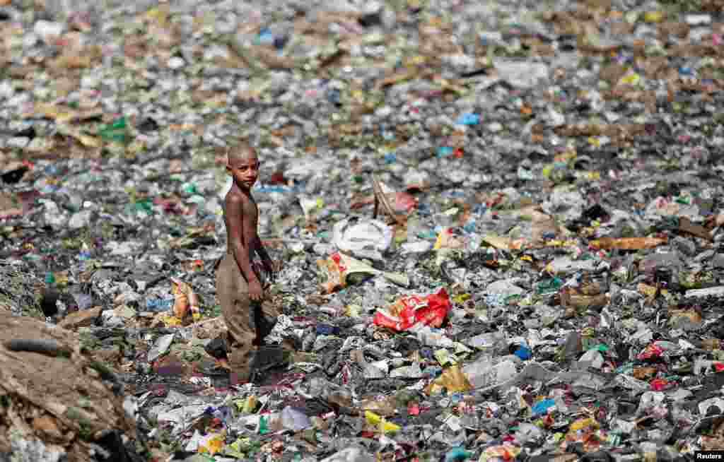 Seorang anak pemulung berjalan di antara tumpukan sampah di New Delhi, India.