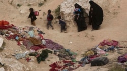 FILE - In an image taken on March 14, 2019, women and children depart besieged Islamic State-held village of Baghouz, where an international aid group says it recorded 31 deaths in the final week of that month.