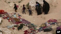 FILE - In an image taken on March 14, 2019, women and children depart besieged Islamic State-held village of Baghouz, where an international aid group says it recorded 31 deaths in the final week of that month.