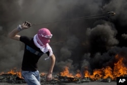 A Palestinian swings a sling during clashes with Israeli troops, near Ramallah, West Bank, Oct. 20, 2015.