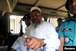 FILE - Bangladesh's Jamaat-e-Islami leader Abdul Quader Mollah talks from a police van after a war crimes tribunal sentenced him to life imprisonment in Dhaka.