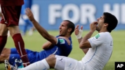 Uruguay's Luis Suarez holds his teeth after running into Italy's Giorgio Chiellini's shoulder during the group D World Cup soccer match between Italy and Uruguay at the Arena das Dunas in Natal, Brazil, Tuesday, June 24, 2014.