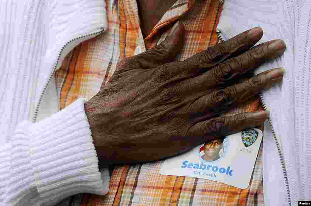 Hattie Wilson places her hand over her heart during the singing of the National Anthem as she mourns her nephew Det. Joseph Seabrook during memorial observances held at the site of the World Trade Center in New York, Sept. 11, 2014.