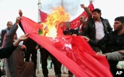 FILE - Protesters burn a Turkish flag during a demonstration calling for the withdrawal of Turkish troops from northern Iraq, in Basra, Iraq, Dec. 18, 2015.