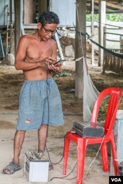 Khon Kheap accesses the news via a smartphone at his home in Prey Veng province. He recently invested some money in a sound system that allows him to play the news broadcasts from his phone on a loudspeaker so that his fellow villagers can get access to news of the day. (Khan Sokummono/VOA Khmer)