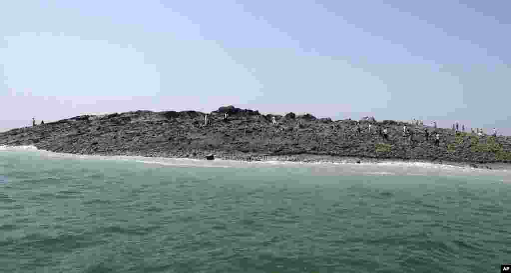 People walk on an island that reportedly emerged off the Gwadar coastline in the Arabian Sea.&nbsp;A deadly magnitude 7.7 earthquake struck in the remote district of Awaran in Pakistan&#39;s Baluchistan province with enough force to create a small island visible off the southern coast, Pakistani officials said.
