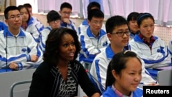 U.S. first lady Michelle Obama (L) sits in for an English class with students at Chengdu No. 7 High School during her visit in Chengdu, Sichuan province, March 25, 2014.