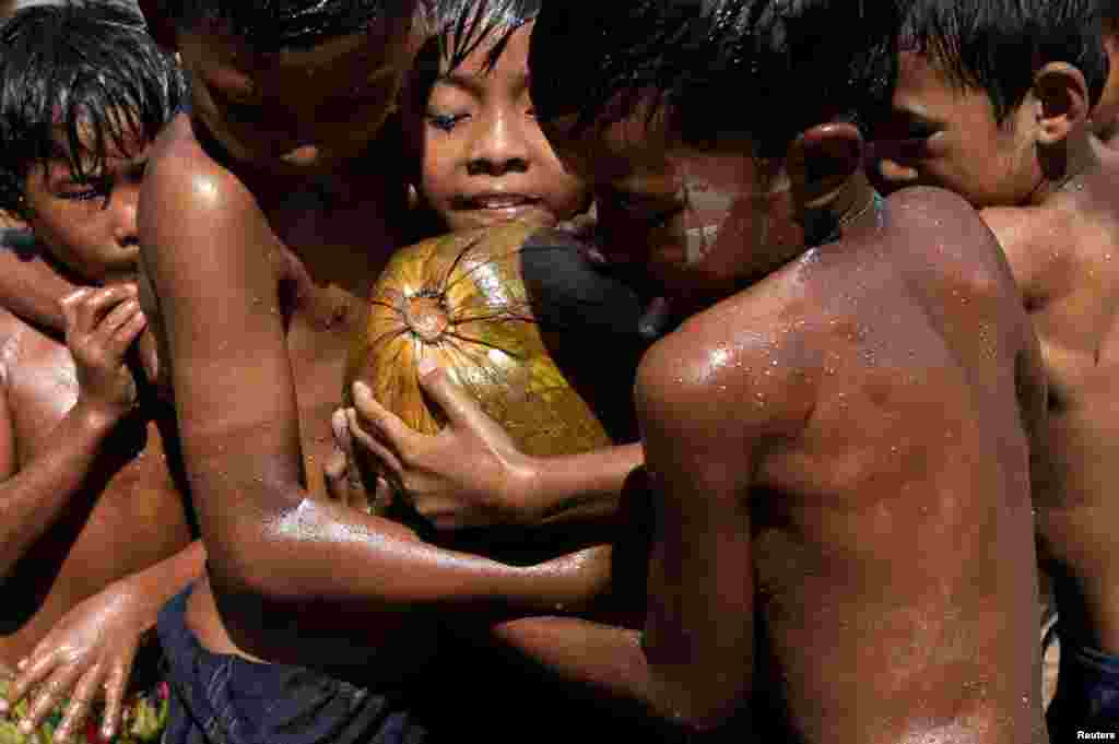 Children play with an oiled coconut during Myanmar&#39;s 73rd Independence Day celebrations in Yangon.