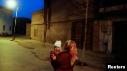 資料照：中國新疆喀什一名維吾爾族婦女抱著一個孩子。 （2017年3月23日）