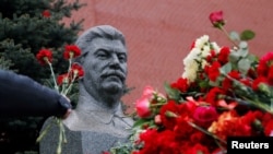 FILE: An attendee offers flowers during a ceremony marking the 66th anniversary of Soviet leader Joseph Stalin's death in Red Square, Moscow, Russia March 5, 2019.