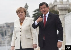 Turkish Prime Minister Ahmet Davutoglu, right, talks to Germany's Chancellor Angela Merkel, left, during their meeting on the grounds of his office in Dolmabahce Palace in Istanbul, Oct. 18, 2015.