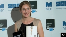 New Zealand writer Eleanor Catton poses after being announced the winner of the Man Booker Prize for Fiction, holding her prize and her book for the photographers, in central London, Oct. 15, 2013. 