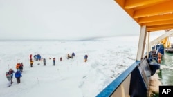 People gather on the ice next the Russian ship MV Akademik Shokalskiy that is trapped in thick Antarctic ice 1,500 nautical miles south of Hobart, Australia, Dec. 27, 2013.