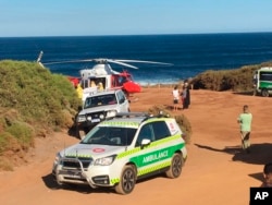 FILE - A rescue helicopter and other emergency vehicles are seen at the scene of the shark attack in Gracetown, Australia.