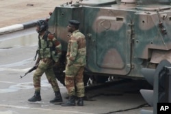 Armed soldiers stand by an armored vehicle on the road leading to President Robert Mugabe's office in Harare, Zimbabwe, Nov. 15, 2017.