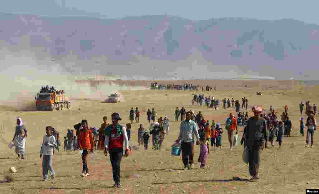 Displaced people from the minority Yazidi sect, fleeing violence from forces loyal to the Islamic State in Sinjar town, walk towards the Syrian border, on the outskirts of Sinjar mountain, near the Syrian border town of Elierbeh of Al-Hasakah Governorate, Aug. 11, 2014.