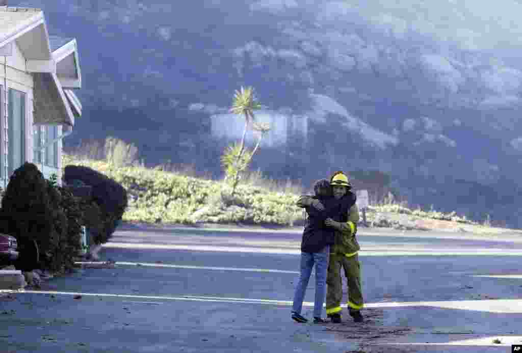 Firefighter Simon Garcia, of Heartland Fire Dept., gets a hug from a woman who did not give her name after she arrived to find her house was intact in the Rancho Monserate Country Club, Dec. 8, 2017, in Fallbrook, California. 