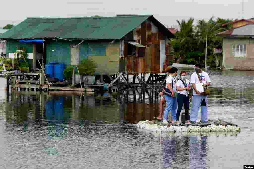 Healthcare workers ride on a makeshift raft during the house to house vaccination of bedridden citizens for the COVID-19 in Valenzuela City, Metro Manila, Philippines, July 6, 2021.