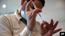 Seorang pekerja medis menyiapkan botol vaksin virus corona Pfizer di pusat Layanan Kesehatan Clalit di Yerusalem, 22 September 2021. (Foto: AP)