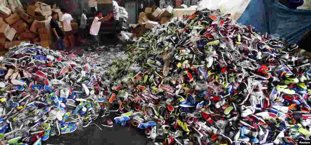 Government workers from the Bureau of Customs destroy counterfeit footwear products in Manila, the Philippines. A government statement said over 150,000 pairs of fake shoes and slippers of various brands including Nike, Adidas, Converse, Sketchers, North Face, Leaveland, Merrell, Lacoste, Vans, Havaianas and Ipanema worth PHP 50 million ($1.13 million), which were smuggled from China, were destroyed at a government warehouse in Manila.