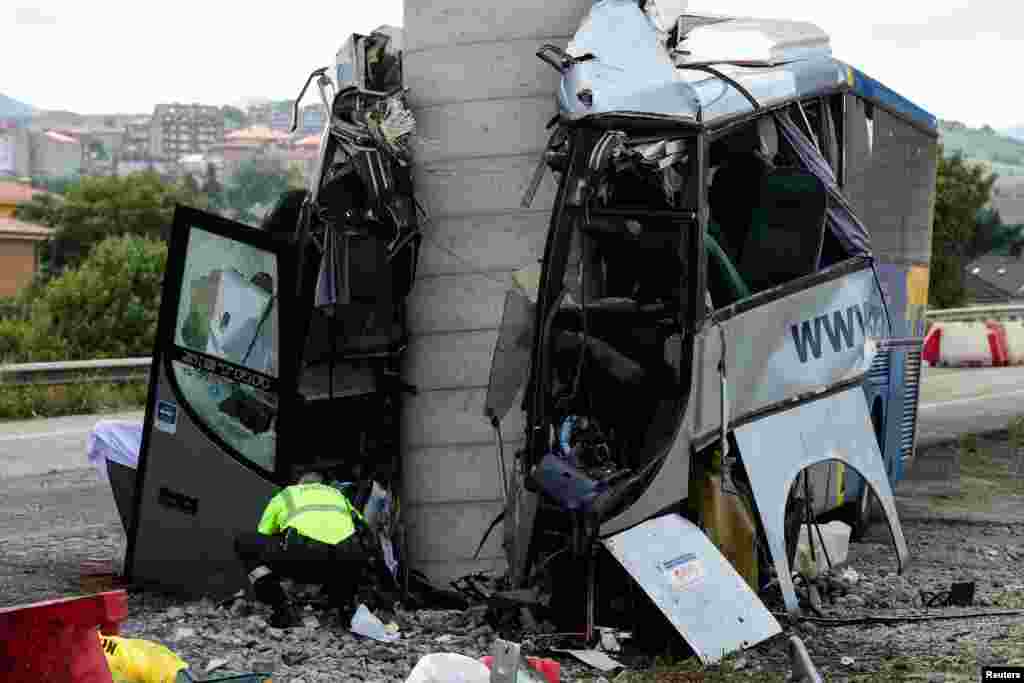 A civil guard surveys the wreckage of a bus crash which left at least four people dead in Aviles, Spain.