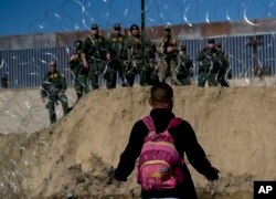 A Honduran migrant converses with U.S border agents on the other side of razor wire after they fired tear gas at migrants pressuring to cross into the U.S. from Tijuana, Mexico, Nov. 25, 2018.