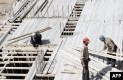 FILE - Members of a construction crew work at a site for new apartment buildings in Damascus, Syria.