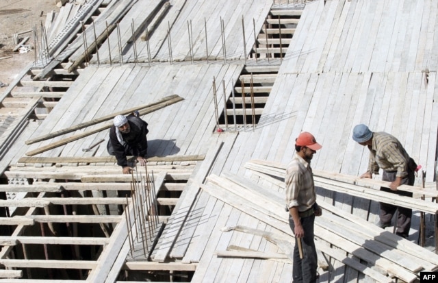 FILE - Members of a construction crew work at a site for new apartment buildings in Damascus, Syria.