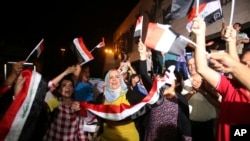 Iraqis celebrate while holding national flags in Tahrir square in Baghdad, Iraq, July 10, 2017. 