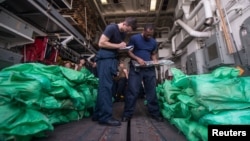ນັກຊ່ຽວຊານຈາກບໍລິສັດ Ensign Sean Standard and Logistics Specialist ກໍາລັງຈົດລາຍການປືນອາກາ ຈໍານວນ ຫລາຍກວ່າ 1,000 ກະບອກ ທີ່ຖືກຢຶດໂດຍກໍ່າປັ່ນລົບຕິດລູກສອນໄຟນໍາວິຖີ USS Jason Dunham ຂອງກອງທັບເຮືອທີ 5 ຂອງສະຫະລັດນັ້ນ ຢູ່ອ່າວ ເອເດນ ໃນວັນທີ 28 ສິງຫາ 2018.