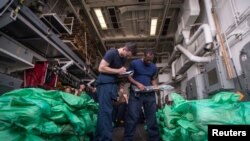 Ensign Sean Standard dan Spesialis Logistik 2nd Class Ray Sanders, memeriksa persediaan cache lebih dari 1.000 senapan otomatis AK-47 di teluk hanggar kapal perusak rudal USS Jason Dunham, yang disita dari kapal tradisional, atau kapal layar di Teluk Aden, 28 Agustus 2018.(Foto: dok).