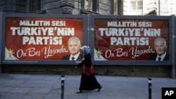 A woman passes a picture of the Turkish Prime Minister Binali Yildirim for the 15th anniversary of AKP party as the sign reads ''The people's voice, Turkey's party, it's now fifteen years old'' in Istanbul, Monday, Aug. 15, 2016.