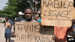 Des manifestants tiennent des affiches avec la mention "Kabila dégage" et "la transition sans Kabila" près de la résidence de l’opposant Félix Tshisekedi, à Limete, Kinshasa, RDC, 30 novembre 2017.