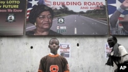 A Liberian child stands in front of an election poster for President Ellen Johnson Sirleaf in the Liberian capital Monrovia, September 8, 2011.