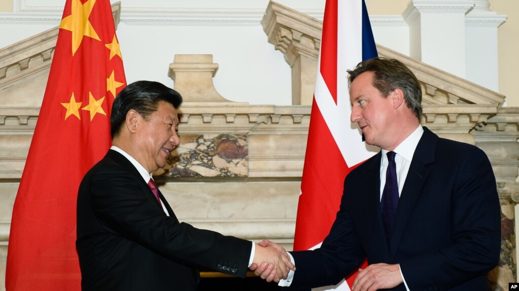 资料照：2015年10月21日时任英国首相卡梅伦(右)与中国国家主席习近平在英中商业峰会上握手。(photo:VOA)