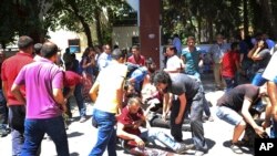 People help the wounded after an explosion in the southeastern Turkish city of Suruc near the Syrian border, Turkey, July 20, 2015.