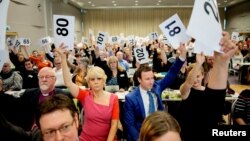 Norwegian Church Council leader Kristin Gunleiksrud Raaum, in red, and Chairman of the Oslo diocesan council Gard Sandaker-Nielsen, right, vote on a proposal to allow same-sex marriage within the Norwegian Church, in Oslo, Norway, April 11, 2016. 