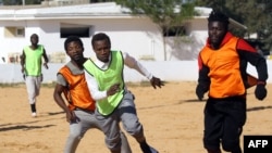 Des migrants camerounais (orange) et sénégalais (jaunes), répartis en deux équipes, participent à un match de football au refuge d'immigration clandestine du ministère libyen de l'Intérieur à Tajoura, le 28 février 2018.
