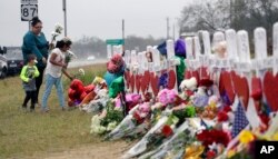 FILE - Mourners visit a makeshift memorial for the victims of the shooting at Sutherland Springs Baptist Church in Sutherland Springs, Texas, Nov. 12, 2017.