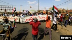 Protesters carry a banner and national flags as they march against the Sudanese military's recent seizure of power and ousting of the civilian government, in the streets of the capital Khartoum, Sudan, Oct. 30, 2021.
