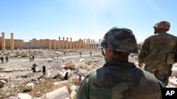 In this picture taken Friday, April 1, 2016, soldiers look over damage at the historical Bel Temple in the ancient city of Palmyra in the central city of Homs, Syria.