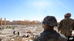 In this picture taken Friday, April 1, 2016, soldiers look over damage at the historical Bel Temple in the ancient city of Palmyra in the central city of Homs, Syria.