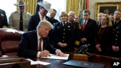 President Donald Trump signs the first veto of his presidency in the Oval Office of the White House, March 15, 2019, in Washington. Trump issued the veto to protect his emergency declaration for border wall funding.