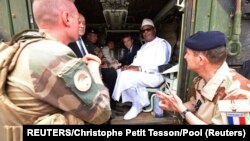 Le président français Emmanuel Macron (au centre) avec le président malien de l'époque Ibrahim Boubacar Keita (à droite) à l'intérieur d'un véhicule militaire alors qu'ils rendent visite aux troupes françaises à Gao, dans le nord du Mali, le 19 mai 2017.
