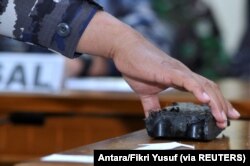 Personel TNI AL membawa puing-puing yang diyakini berasal dari kapal selam TNI AL KRI Nanggala-402 yang hilang, ditampilkan saat jumpa pers di Bandara I Gusti Ngurah Rai, Bali, 24 April 2021. (Foto: Antara/Fikri Yusuf via REUTERS)