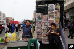 A street vendor waits for clients on the sidelines of a protest against the IMF World Bank, which are holding their annual meetings in Lima, Peru, Oct. 9, 2015.
