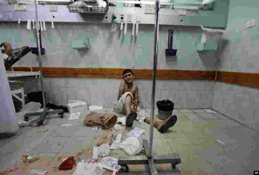 A Palestinian boy, who was wounded in an Israeli strike on a house in Beit Lahiya, northern Gaza Strip, sits on the floor as he waits to be treated at the emergency room of the Kamal Adwan hospital, in Beit Lahiya.